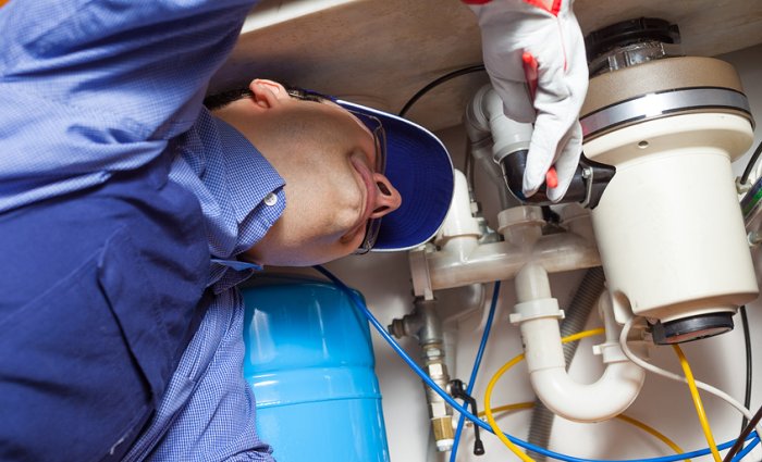 man in blue shirt installing garbage disposal