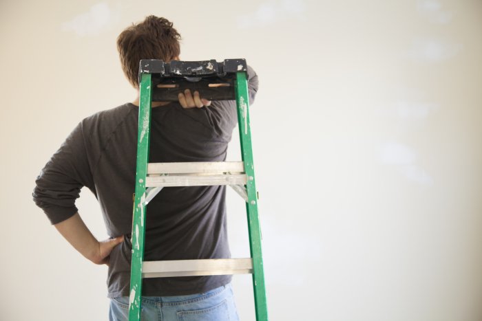painter holding ladder behind back
