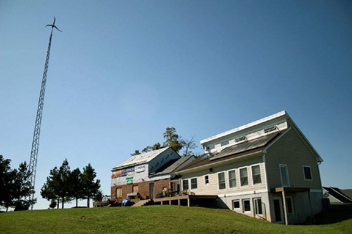A home with solar panels and a wind turbine
