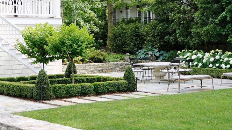 Backyard landscaping with patio table and chairs next to grass