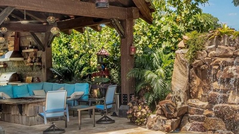 Outdoor area with grill and furniture around fire pit and rocky waterfall