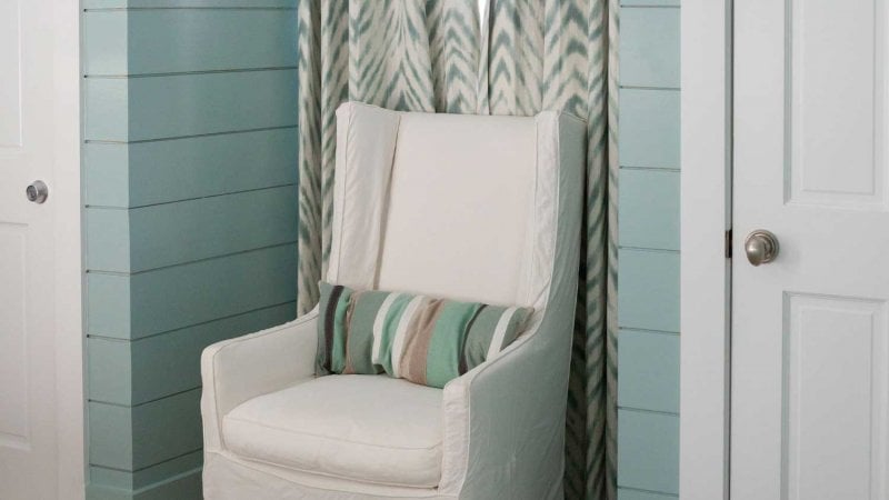 Bedroom with blue shiplap walls and a white armchair in an alcove (Photo by KCULP - stock.adobe.com)