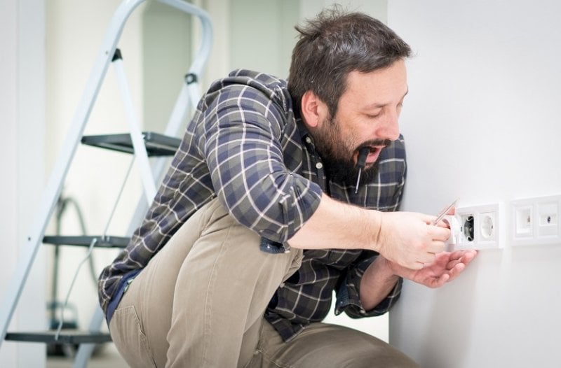 Man fixing electrical outlet (Photo by Jasmin Merdan / Moment via Getty Images)