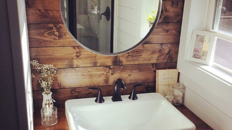 Small bathroom sink, wood shiplap accent wall, and circle mirror (Photo by Michael - stock.adobe.com)