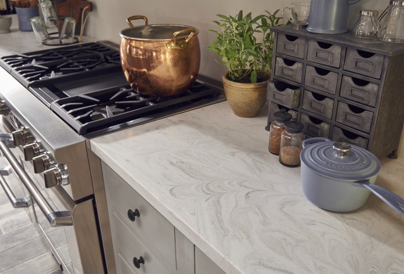 Light Corian kitchen counter around stove with copper pot (Photo by Dupont)