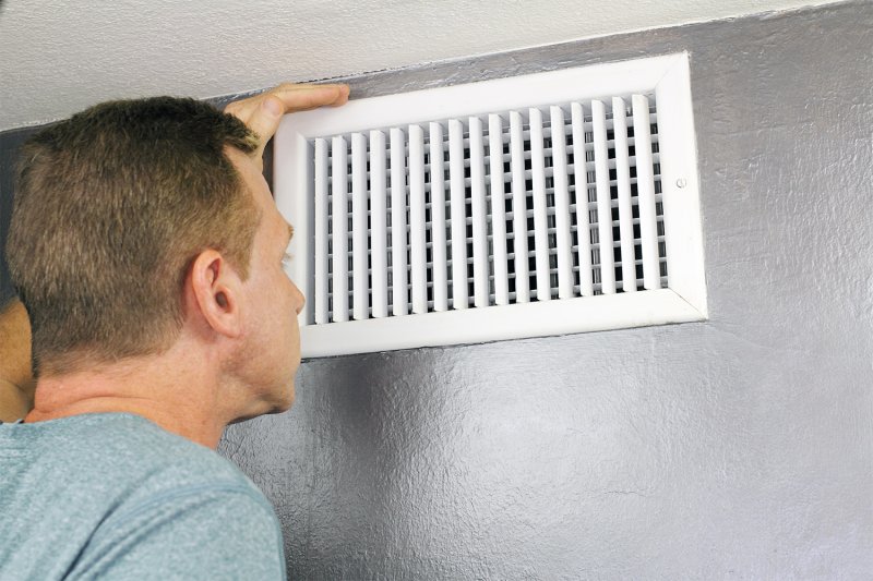 Man inspecting air vent in home (Photo by Serenethos via Getty Images)