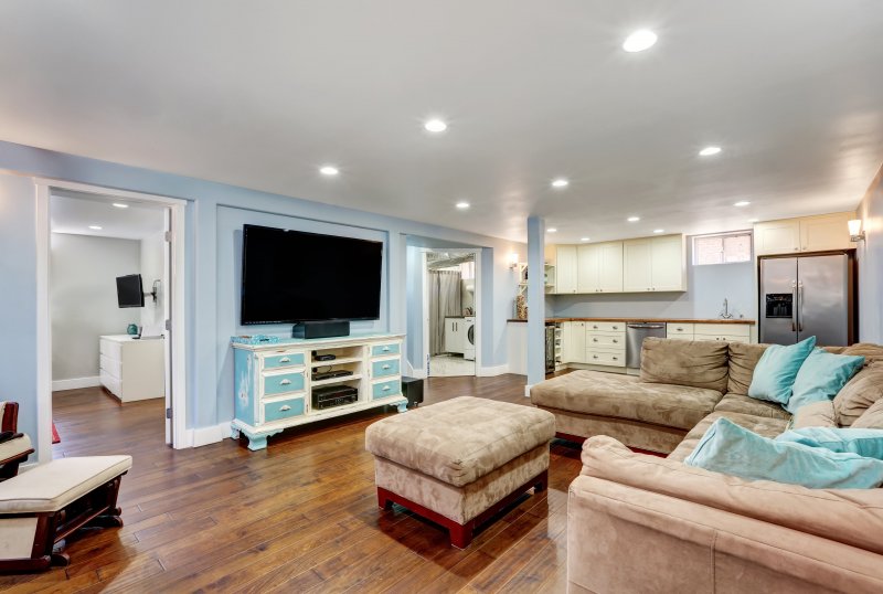Basement living room with pastel blue walls and taupe sectional (Photo by Iriana Shiyan – stock.adobe.com )