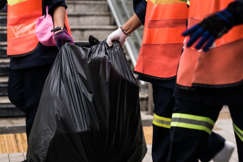 People moving junk in a trash bag (Photo by Araya - stock.adobe.com)