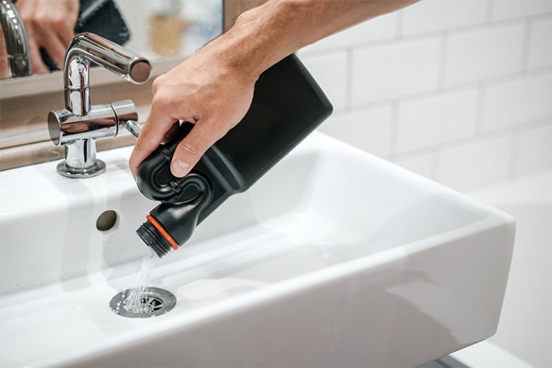 Plumber using chemicals to clean sink drain (Photo by Galaganov - stock.adobe.com )
