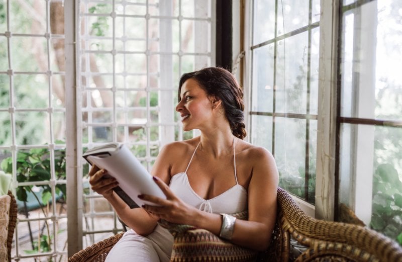 woman reading in sunroom (Photo by Nortonrsx/iStock/Getty Images Plus via Getty Images)