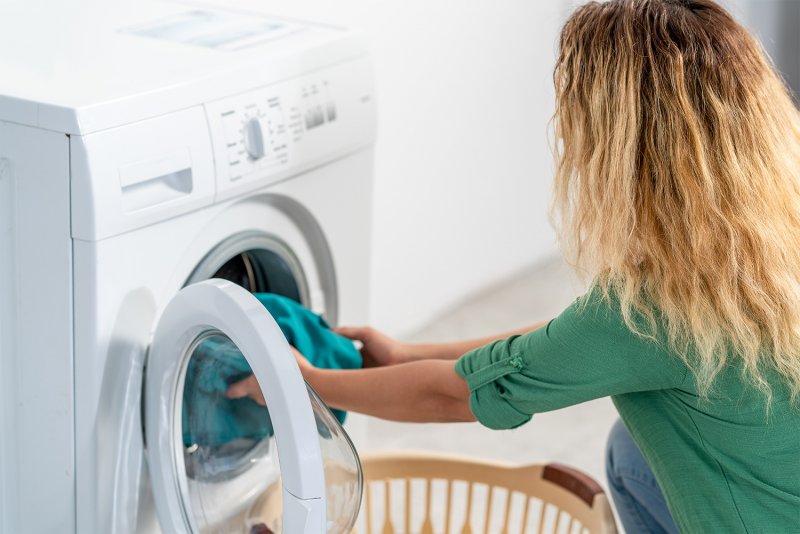 Woman putting laundry in the washing machine (Photo by Sondem - stock.adobe.com)
