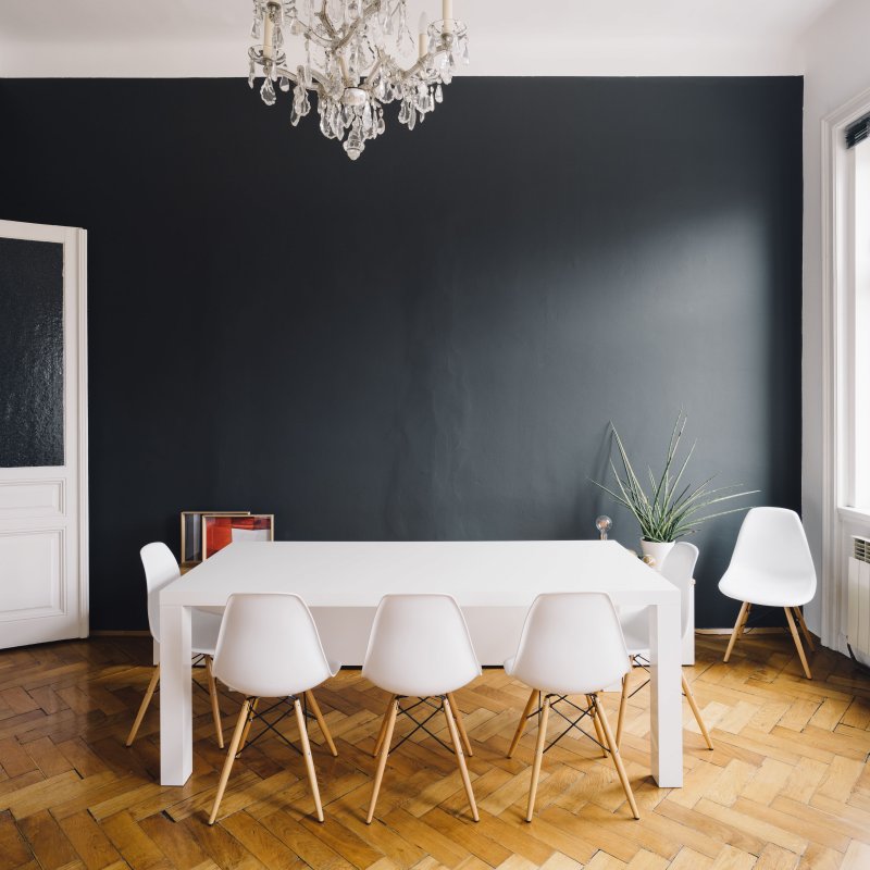 Black accent wall in dining room with white tables and chairs (Photo by Gregor Hofbauer / EyeEm via Getty Images)