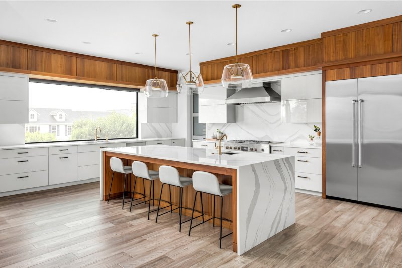 Kitchen with white marble backsplash, marble waterfall island and white cabinets (Photo by bmak - stock.adobe.com)
