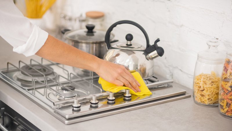 Woman cleans stove (Photo by zinkevych - stock.adobe.com)
