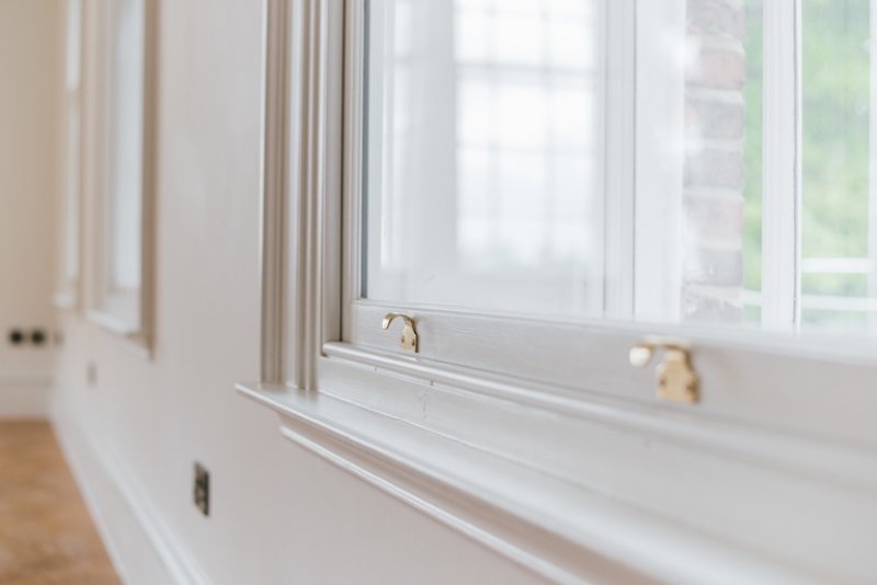 closeup of white window and track with gold lock clasps (Photo by Wirestock - stock.adobe.com)