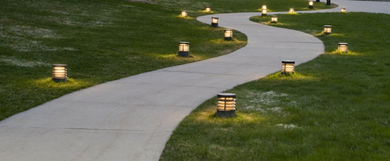 a winding concrete walkway surrounded by grass and lined with lanterns (Photo by © doug4537/E+/Getty Images)