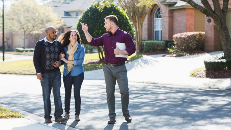 A couple walking with a contractor on a residential road (Photo by kali9/E+ via Getty Images)