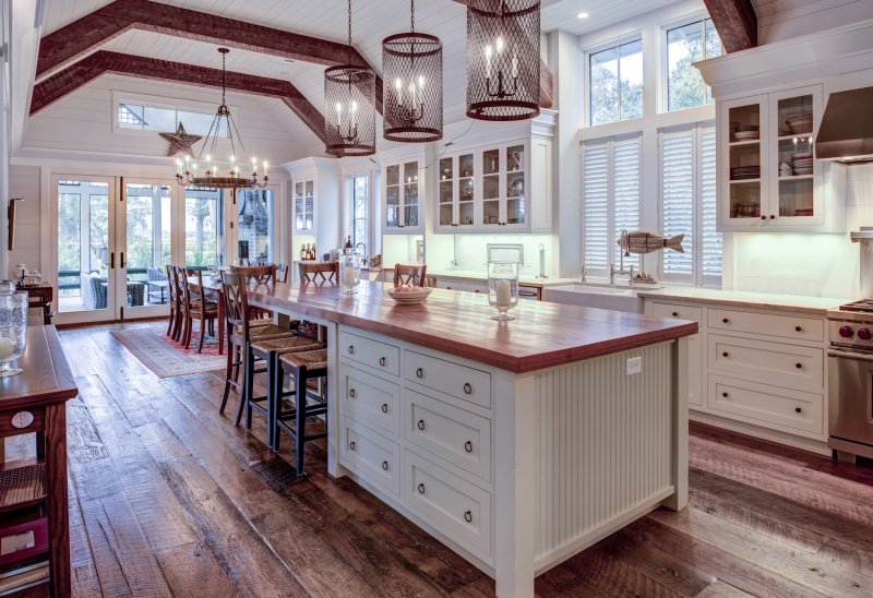 Farmhouse/craftsman kitchen and dining room with hardwood floors, exposed beams, shiplap ceiling, and big center island (Photo by Wollwerth Imagery - stock.adobe.com)