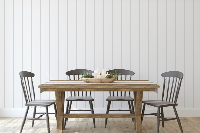 Farmhouse dining table and chairs in front of white vertical shiplap accent wall (Photo by poligonchik - stock.adobe.com)