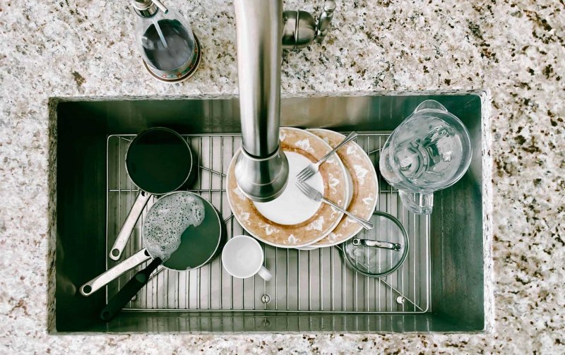 Dirty dishes sitting in a sink on a metal grid (Photo by Grace Cary/Moment via Getty Images)
