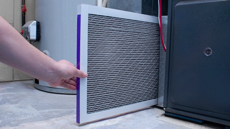 Person changing air filter on furnace (Photo by Marvin Samuel Tolentino Pineda/ iStock via Getty Images)