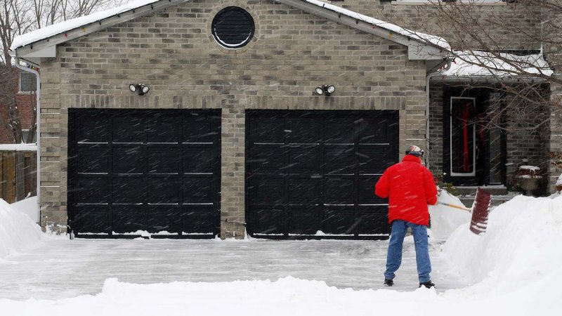 Man shoveling snow outside garage (Photo by Les Palenik - stock.adobe.com)