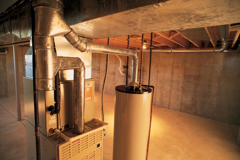 Hot water heater , gas furnace and air conditioning unit in plain, bare basement (Photo by Comstock/Stockbyte via Getty Images)