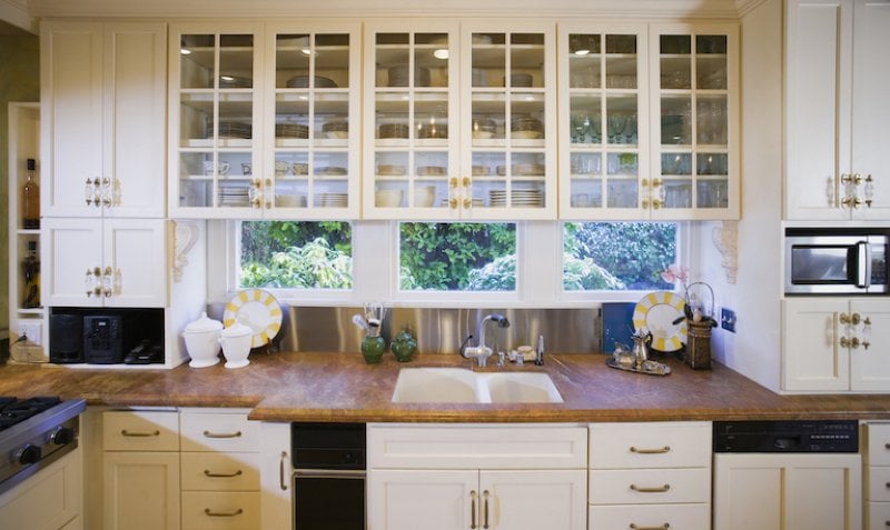 kitchen with windows, wood countertop, and cream cabinets with glass (Photo by Andersen Ross/DigitalVision via Getty Images)