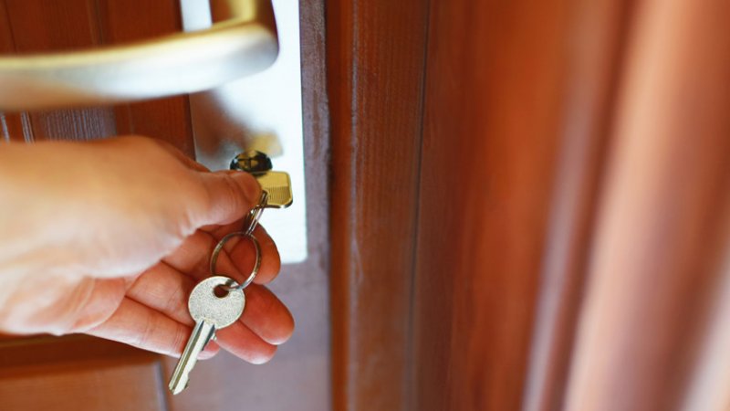 A hand unlocks a door by using a key (Photo by inga/iStock / Getty Images Plus via GettyImages)