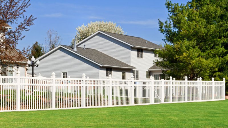 A white vinyl fence enclosing a backyard (Photo by © ghornephoto/Getty Images)