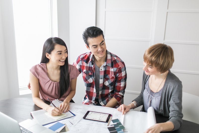three adults look over home designs and paint color options (Photo by ZeroThree - stock.adobe.com)
