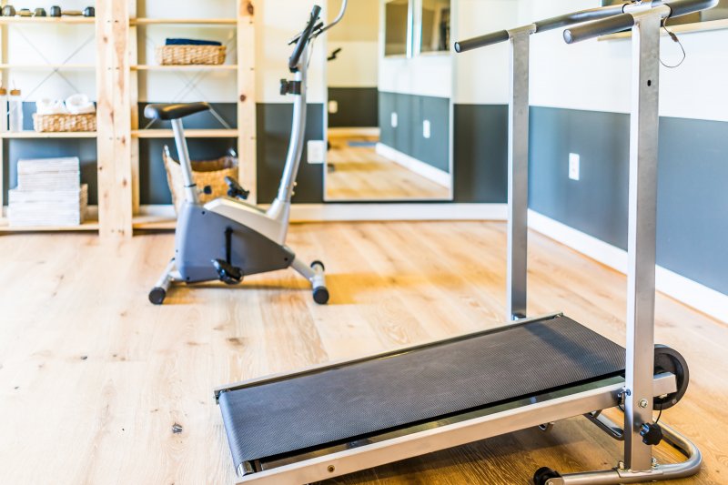 Simple modern home gym with a treadmill, stationary bike, and mirror (Photo by Kristina Blokhin - stock.adobe.com)