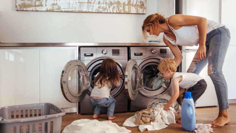 A mom with her children loading the washing machine with clothes (Photo by jacoblund/iStock/Getty Images Plus via Getty Images)