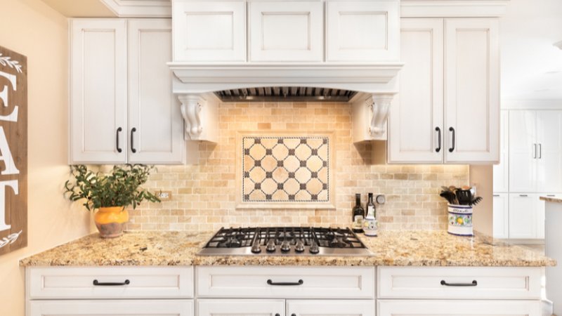 Tan natural stone backsplash and kitchen stove (Photo by Joe Hendrickson/Shutterstock.com)
