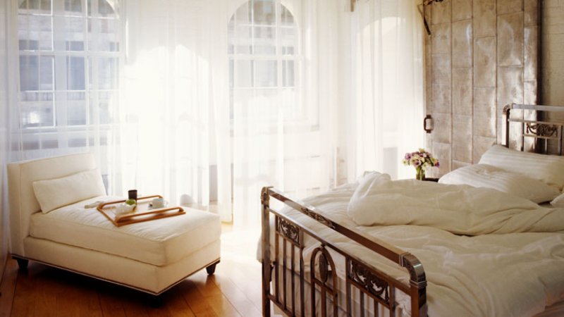 Primary bedroom with floor-to-ceiling windows and a love seat (Photo by © Fernando Bengoechea/Getty Images )