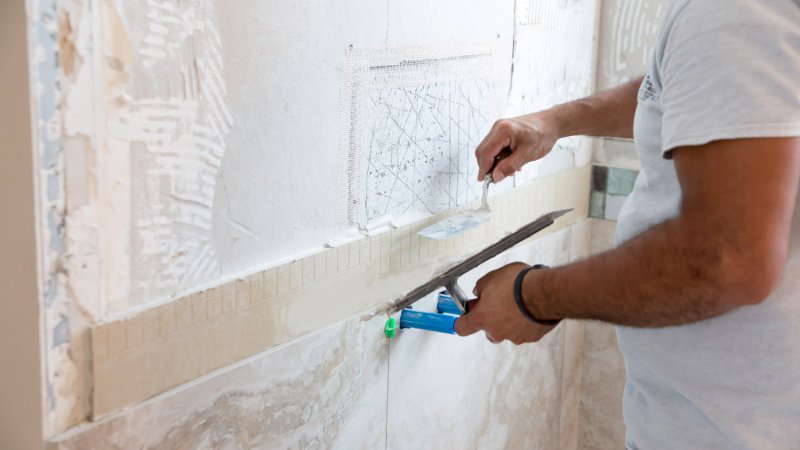 A professional laying new tiles in a shower (Photo by Jodi Jacobson/E+ via Getty Images)
