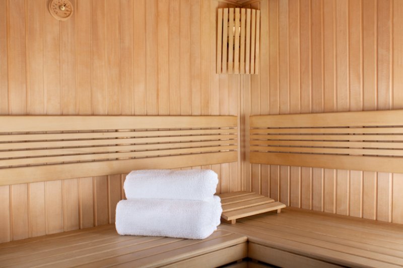 closeup of sauna benches and walls with white towels folded on the bench (Photo by © Loraliu - stock.adobe.com)