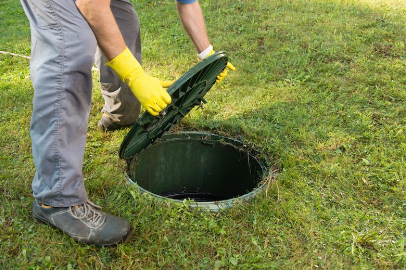 a man lifting a septic tank lid off of the septic tank (Photo by © kaliantye - stock.adobe.com)
