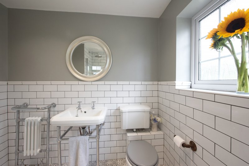 Industrial vessel bathroom sink on wood vanity below industrial pendant lamp and three mirrors (Photo by John Keeble / Moment via Getty Images)
