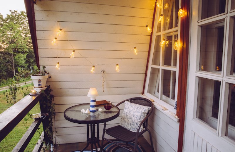 small patio with round coffee table and chair, with string lights hanging from ceiling (Photo by FotoHelin - stock.adobe.com)