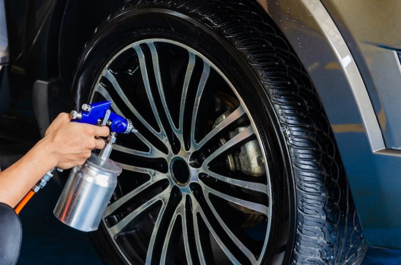 hands holding spray coating, spraying car wheel (Photo by khunkorn - stock.adobe.com)