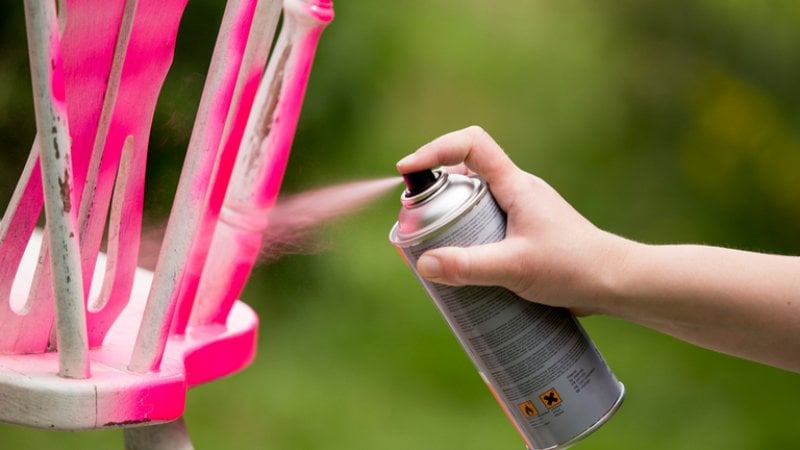 Spray painting an old chair pink (Photo by Levas / Shutterstock.com)