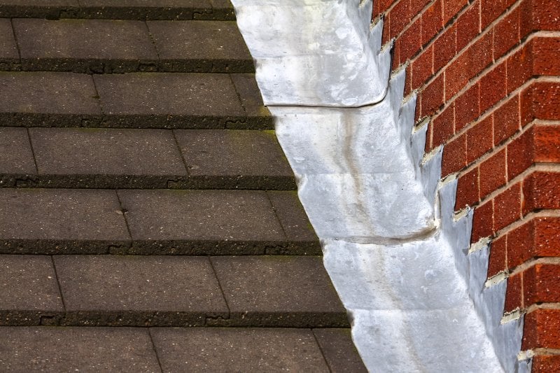 A roof with step flashing going up a brick wall (Photo by Andrew Gardener - adobe.stock.com)