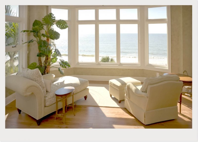 sunroom with chairs and windows with waterfront views (Photo by © DenGuy /Getty Images)