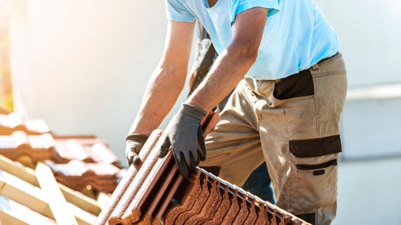 A tiler covering a roof with new tiles (Photo by vitranc/iStock / Getty Images Plus via Getty Images)