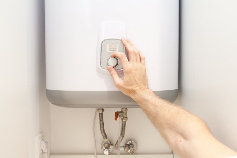 a hand turning the thermostat of a water heater (Photo by © brizmaker/ iStock / Getty Images Plus/Getty Images.)