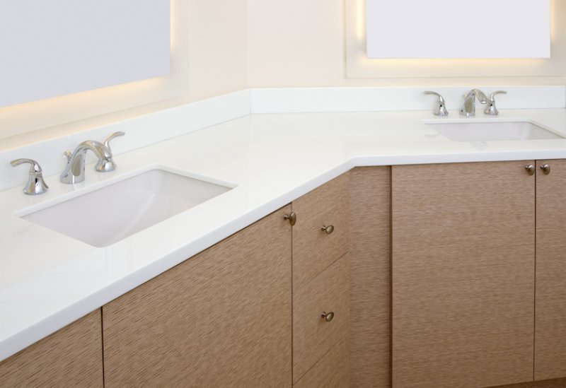 bathroom with white counter, brown cabinets, and backlit mirrors (Photo by bauhaus1000/iStock / Getty Images Plus via Getty Images)