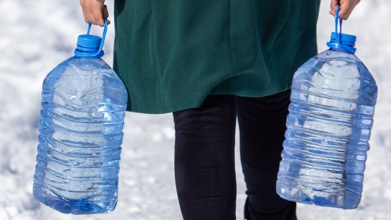 A woman carrying water in plastic bottles (Photo by schankz - stock.adobe.com)