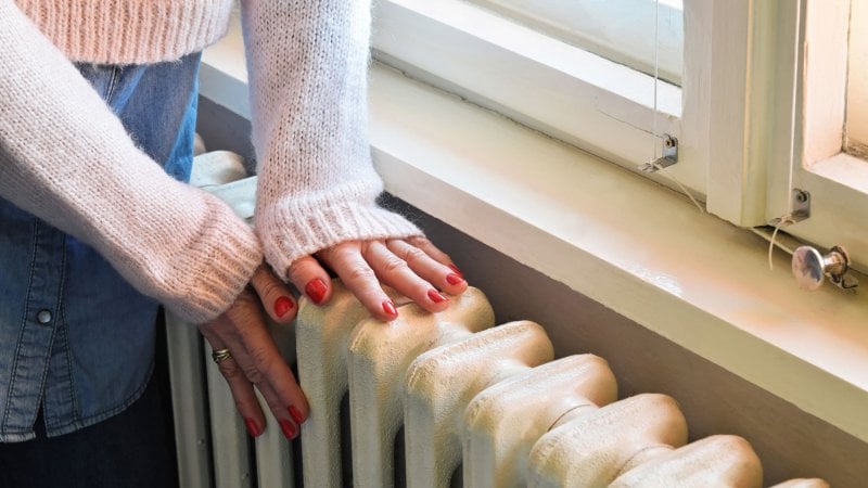 A woman’s hands warming on a radiator (Photo by zvonko1959/iStock/Getty Images Plus via Getty Images)