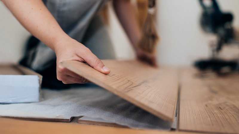 Detail of a woman’s hands installing laminate flooring (Photo by Guido Mieth/DigitalVision via Getty Images)